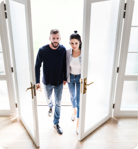 Young couple walking through doors of home