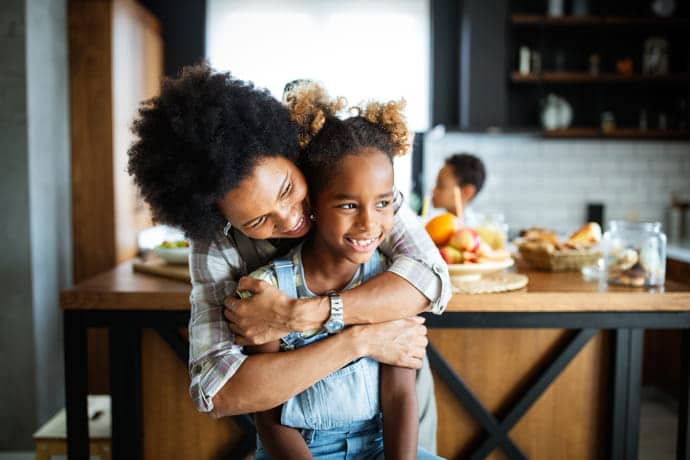 Mother hugging daughter in beautiful kitchen